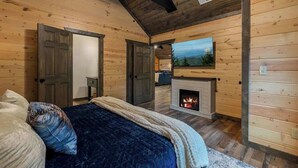 Ein Schlafzimmer in einer Blockhütte mit Kamin, einem Bett mit blauer Decke und einem Bild an der Wand.