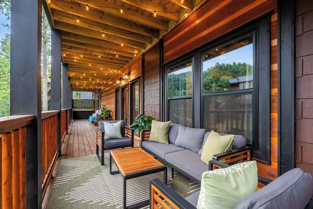A covered outdoor seating area with wooden flooring, a sofa, and a coffee table.
