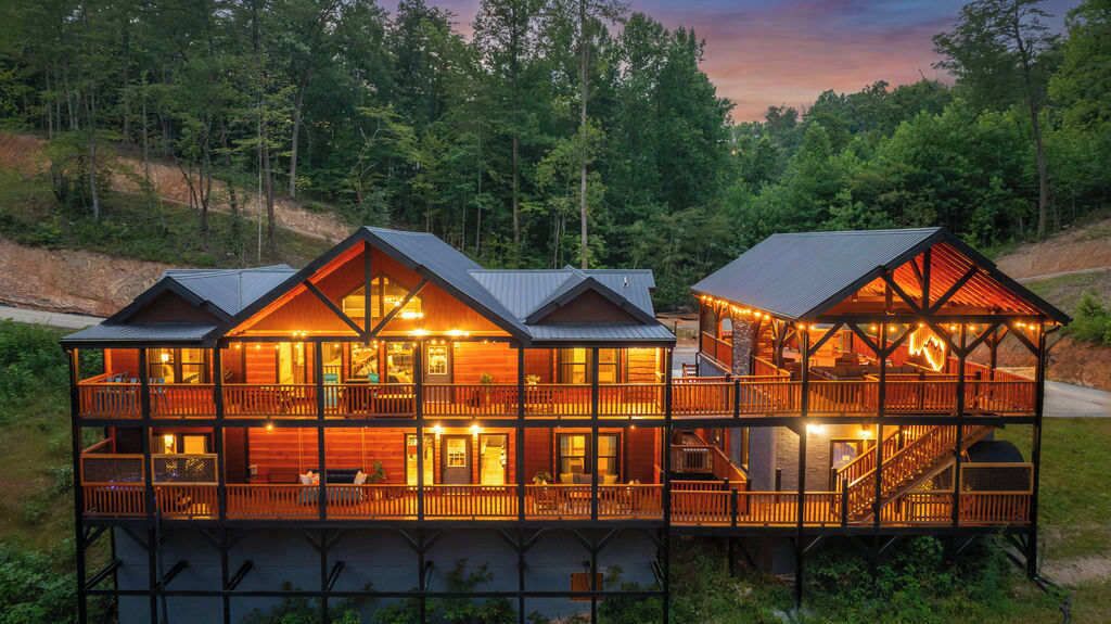 A multi-story wooden cabin with balconies, large windows, and a covered outdoor area.