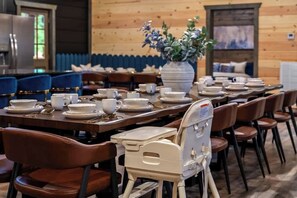 A restaurant with wooden walls, blue chairs, and a white table with plates and cups. - 8-Bedroom Cabin with Themed Indoor Pool, Theater & Arcade Near Pigeon Forge (Sevierville)