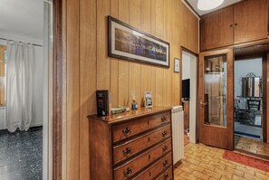 A wooden-paneled room with a large framed picture, a wooden dresser with drawers, and a radiator.