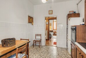 A compact kitchen with a dining table, chairs, a refrigerator, and a wooden cabinet.