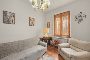 Una sala de estar con dos sofás, una mesa con una lámpara y obras de arte en las paredes.