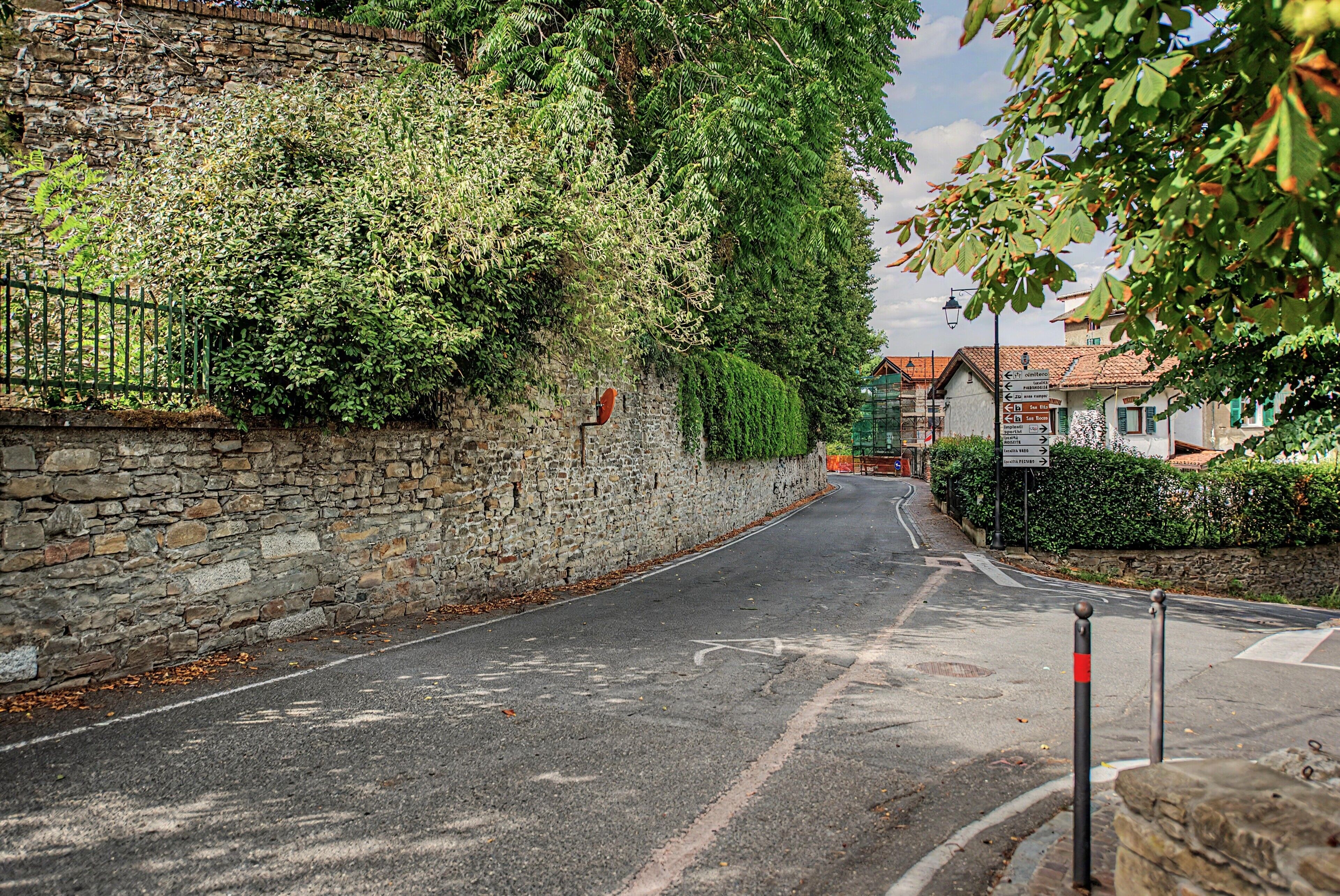 A narrow street with a stone wall on one side and a row of buildings on the other.
