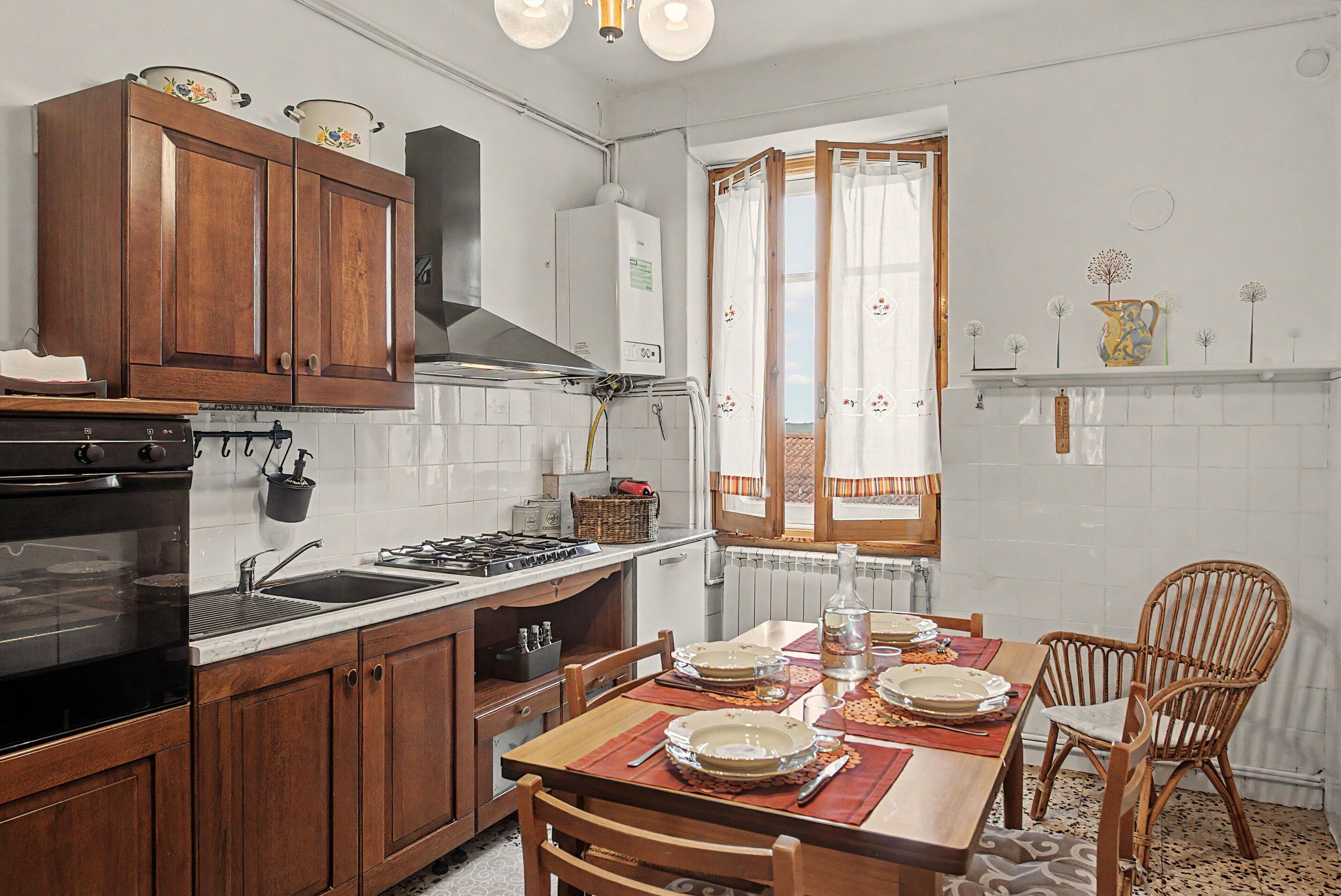 A kitchen with wooden cabinets, a stove, and a dining table set for four.