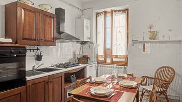 A kitchen with wooden cabinets, a stove, and a dining table set for four.