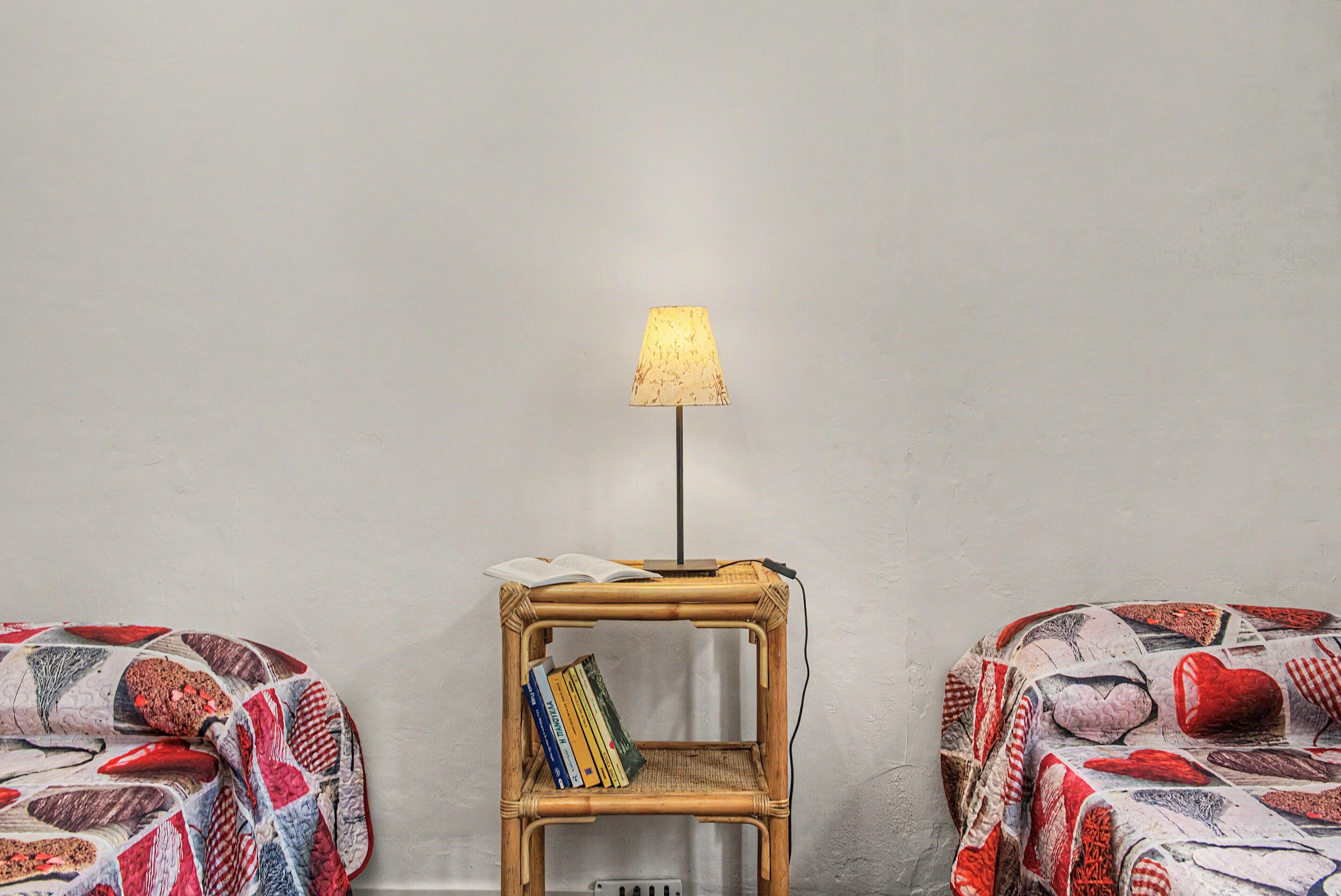 Une chambre avec deux lits, une petite table de chevet avec une lampe et une étagère murale remplie de livres.