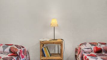 Une chambre avec deux lits, une petite table de chevet avec une lampe et une étagère murale remplie de livres.