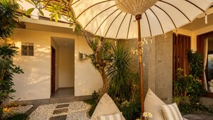 A cozy outdoor seating area with a cushioned sofa, a decorative umbrella, and a garden path. - Pavilion Pool Villa. Walk to Beach (Kecamatan Mengwi,)