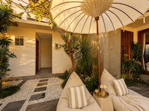 A cozy outdoor seating area with a cushioned sofa, a decorative umbrella, and a garden path. - Pavilion Pool Villa. Walk to Beach (Kecamatan Mengwi,)