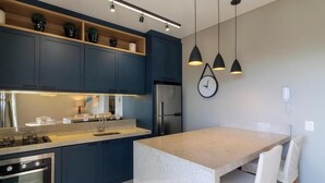 A modern kitchen with dark blue cabinets, a stainless steel refrigerator, and pendant lighting. - Apt in Condo w/ Private BBQ in Center Ilg0307 (Bombinhas)