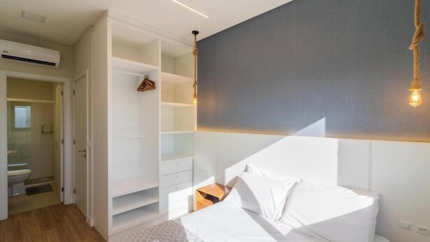 A bedroom with a bed, a wardrobe, and a built-in shelf unit. - Apt in Condo w/ Private BBQ in Center Ilg0307 (Bombinhas)