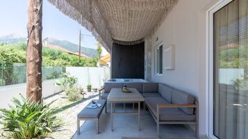 Ein moderner Außenbereich zum Sitzen mit einer Couch, Tischen und einer Pergola.