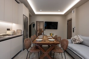 Una cocina moderna con una mesa de comedor para cuatro personas, un sofá y un televisor de pantalla plana montado en la pared.