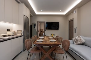 Una cocina moderna con una mesa de comedor para cuatro personas, un sofá y un televisor de pantalla plana montado en la pared.