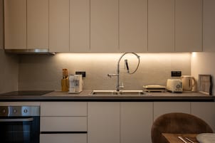Una cocina moderna con lavavajillas incorporado, un lavamanos de acero inoxidable y un tostador.