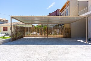 Un espacio al aire libre cubierto con piso de grava, cerca de bambú y un edificio al fondo.
