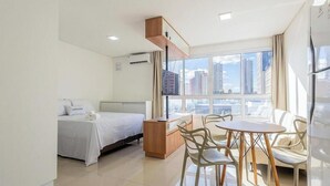 Ein Hotelzimmer mit Bett, Schreibtisch, Stuhl, Fenster mit Stadtblick und Kühlschrank.