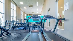 Ein Fitnessstudio mit Laufbändern, Kurzhanteln und Krafttrainingsgeräten.