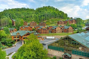 Eine Lodge mit mehreren Holzhäusern, einer zentralen Glasstruktur und einem Waldhang im Hintergrund.
