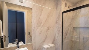 Ein modernes Badezimmer mit Marmorwänden, einer Duschkabine aus Glas und einer blauen Tür.