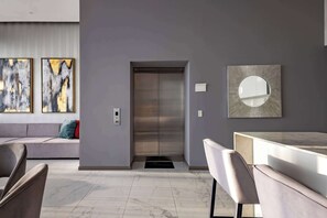 A modern interior with a sofa, chairs, an elevator, and artwork on the walls. - Paradise Awaits | Ocean View Condo (Bucerías)