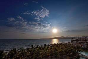 A resort with a pool, palm trees, and a view of the ocean at sunset. - Paradise Awaits | Ocean View Condo (Bucerías)
