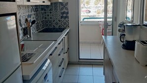 A modern kitchen with a central island, a built-in oven, and a view through the door. - Port Fréjus: harbor view, spacious 1-bedroom apartment (47m²), air conditioning, swimming pool—for 4 lucky guests. (Fréjus)