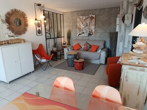 Ein modernes Wohnzimmer mit einer Couch, Sesseln, einem Esstisch und einer Küchenzeile mit Schränken.