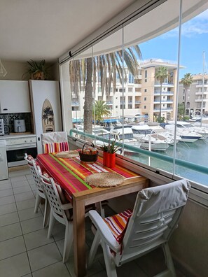 A dining area with a view of a marina, a kitchen with a stove, and a potted plant. - Port Fréjus: harbor view, spacious 1-bedroom apartment (47m²), air conditioning, swimming pool—for 4 lucky guests. (Fréjus)