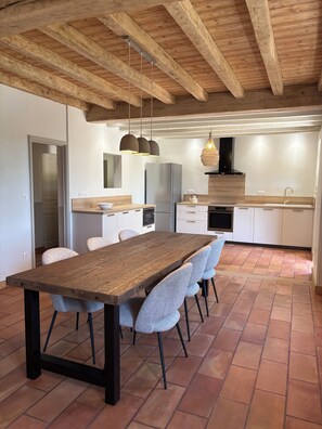 A modern kitchen with a wooden table, chairs, and a tiled floor. - Périgord-style house for 6 people with a pool, in a quiet location with a large garden, 10 minutes from Monpazier (Marsalès)