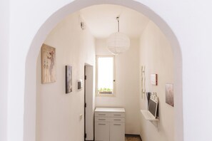 A narrow hallway with an arched ceiling, a white door, and a window with a view of greenery. - PILLY House Ballaró is located in a historic building at the entrance to the Ballaró Market (Palermo)
