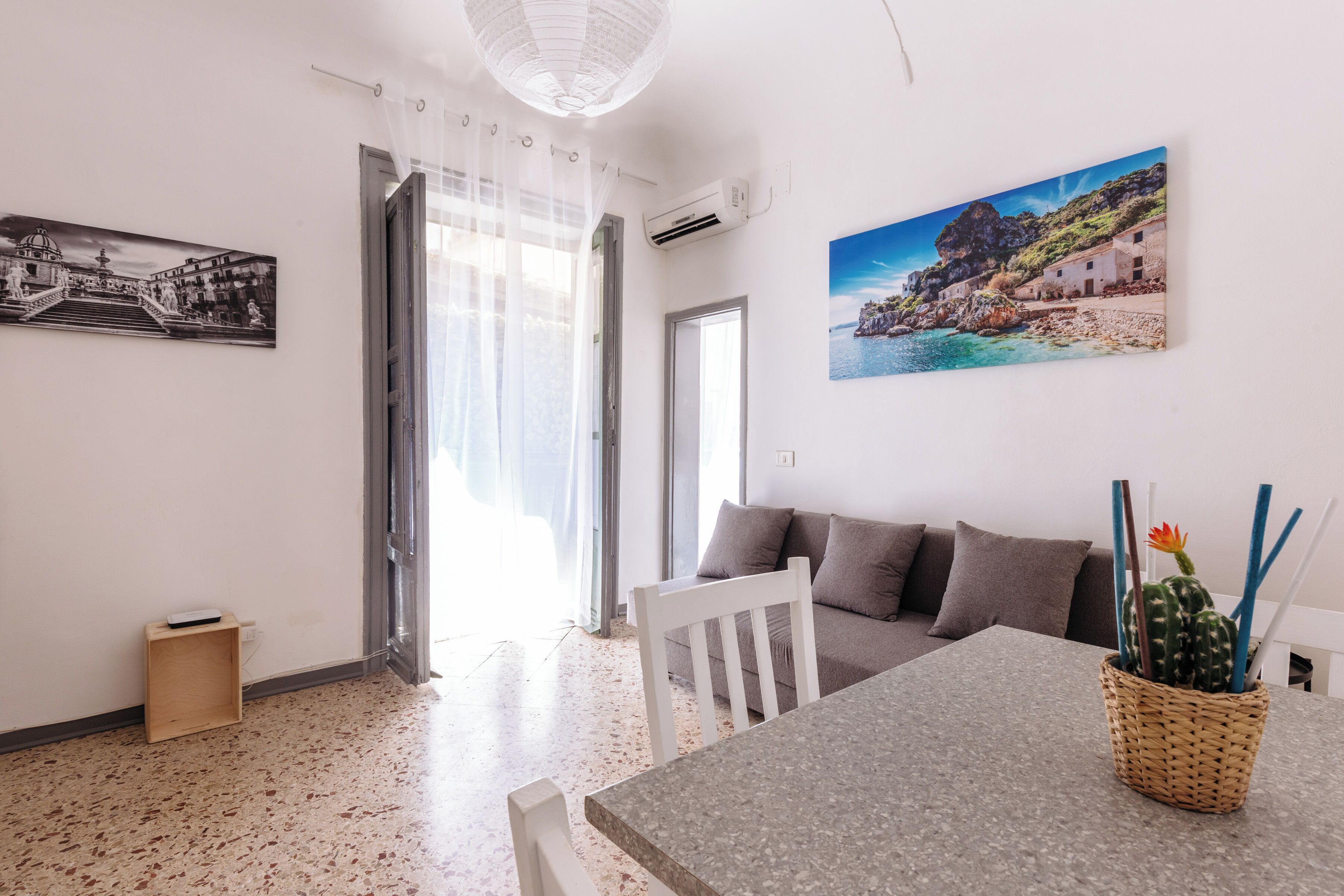 A living room with a sofa, a dining table, and a wall-mounted picture.