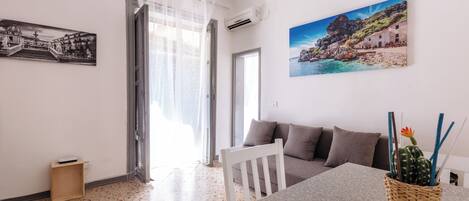 A living room with a sofa, a dining table, and a wall-mounted picture.