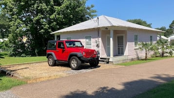Une Jeep rouge était garée devant une maison de plain-pied dotée d’un porche.