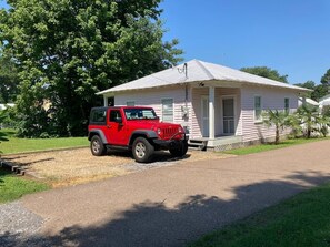 Un jeep rojo estacionado frente a una casa de un piso con porche.