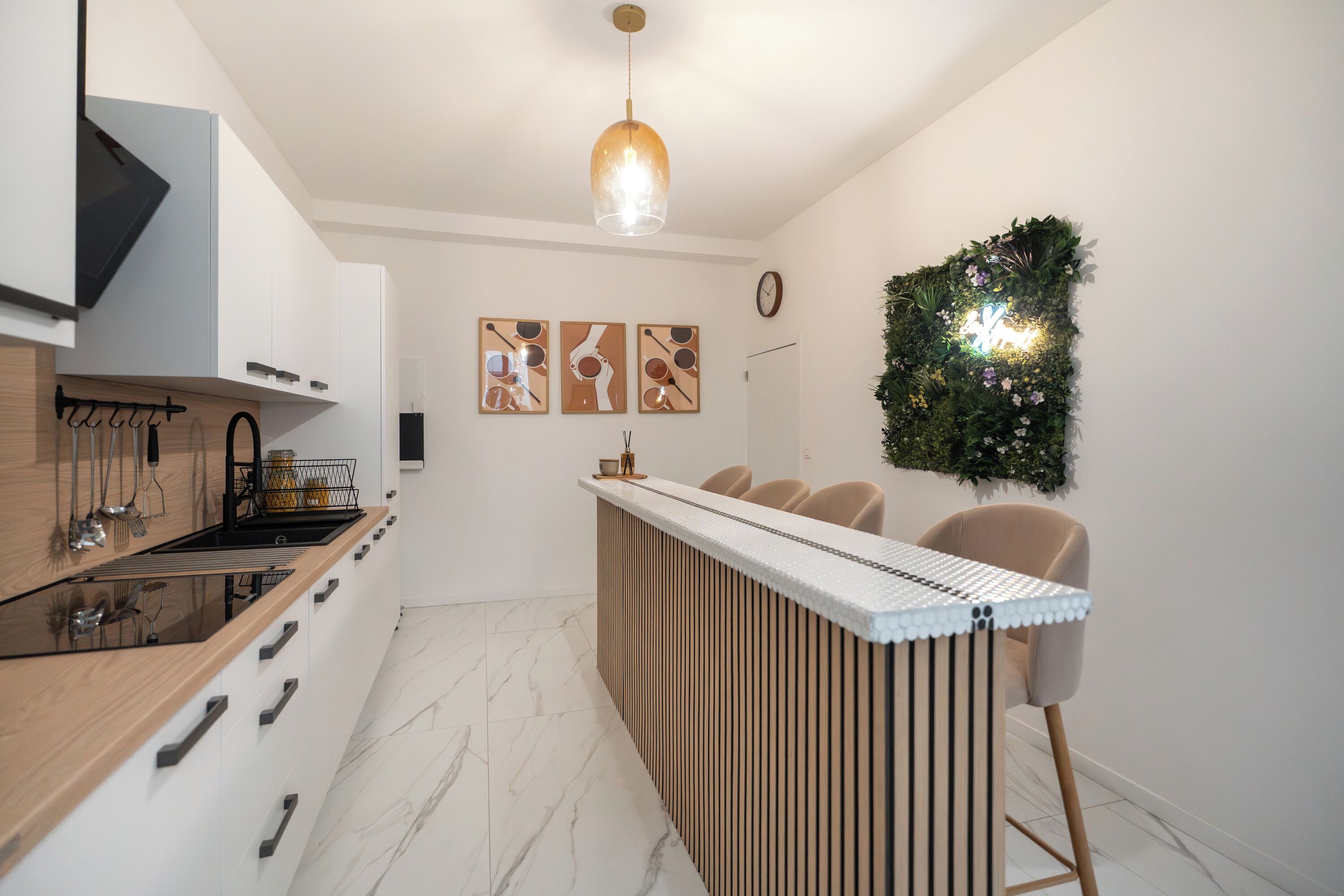 A modern kitchen with a wooden countertop, a built-in stove, and a bar area with chairs.
