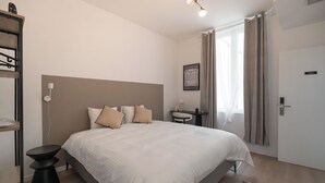 Een slaapkamer met een bed, nachtkastje en een klein bureau.