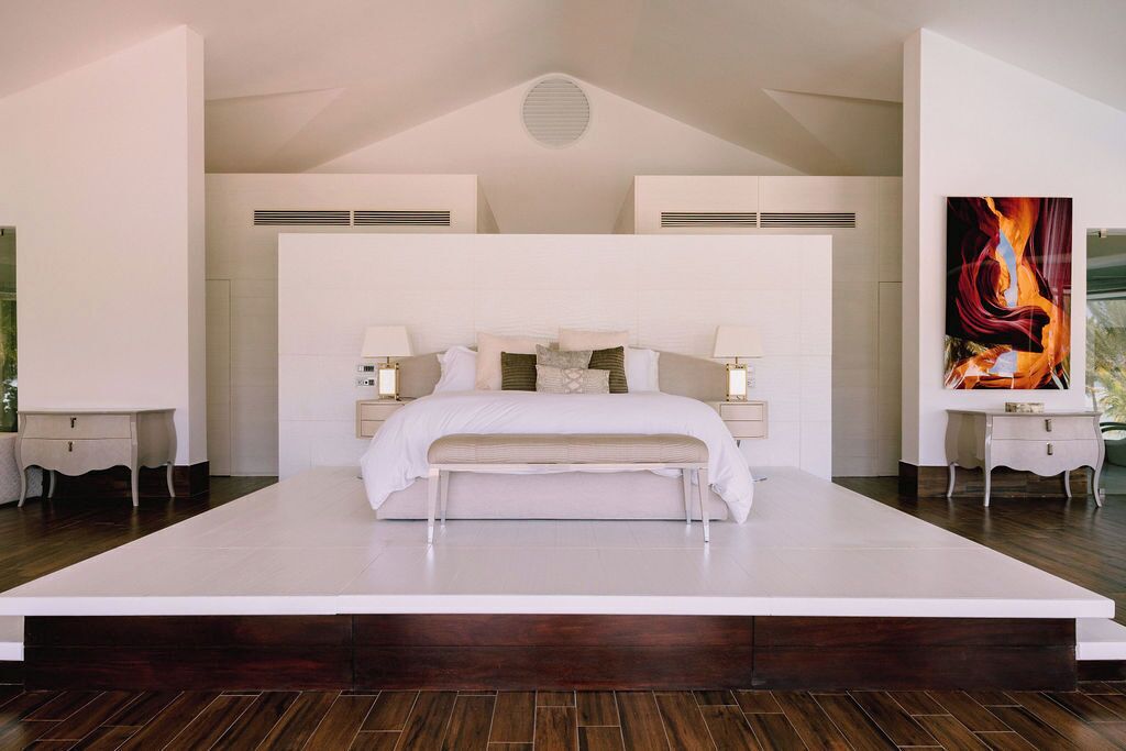 A modern bedroom with a large bed, bedside tables, and a painting on the wall.