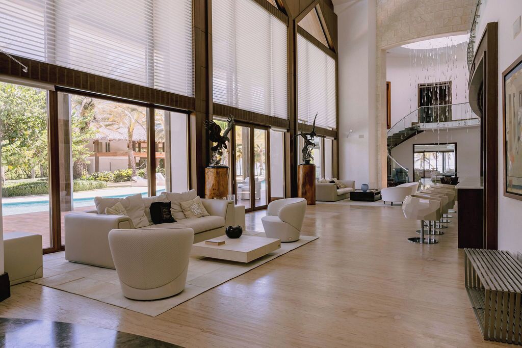 A spacious living area with large windows, a staircase, and a pool view.