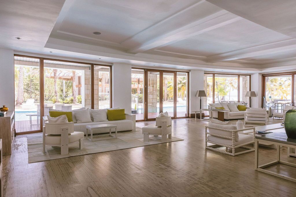 A spacious living area with large windows, a pool view, and a modern interior design.