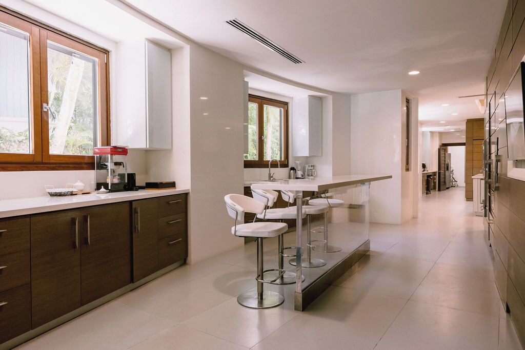 A modern kitchen with a bar area, wooden cabinets, and a large window.