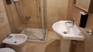 A bathroom with a glass-enclosed shower, a pedestal sink, and a toilet. - Cozy Rooms in the City Center (Reggio Calabria)