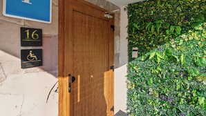 A wooden door with a blue parking sign and two accessibility signs on the wall.