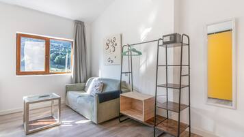 Una sala de estar moderna con un sofá, una mesita, una lámpara colgante y una estantería metálica.