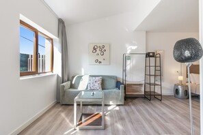 A modern living room with a sofa, a glass coffee table, a floor lamp, and a wall-mounted shelf.