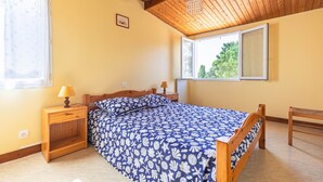 A bedroom with a bed, two bedside tables, a window, and a wooden ceiling. - Duplex No. 2345 – 40m² – Seaside Residence (Port-des-Barques)