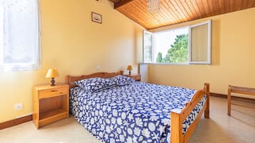 Una camera da letto con un letto, due comodini, una finestra e un soffitto in legno.