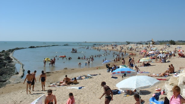 Ein überfüllter Strand mit Menschen, die sich sonnen und schwimmen.