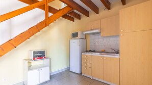 Eine kleine Küche mit integriertem Mikrowellenofen, einem weißen Kühlschrank und Holzschränken.